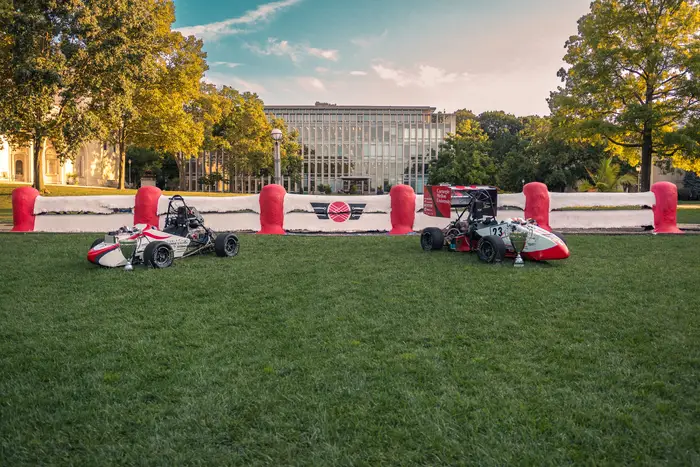 Image of two Carnegie Mellon Racing vehicles in front of The Fence