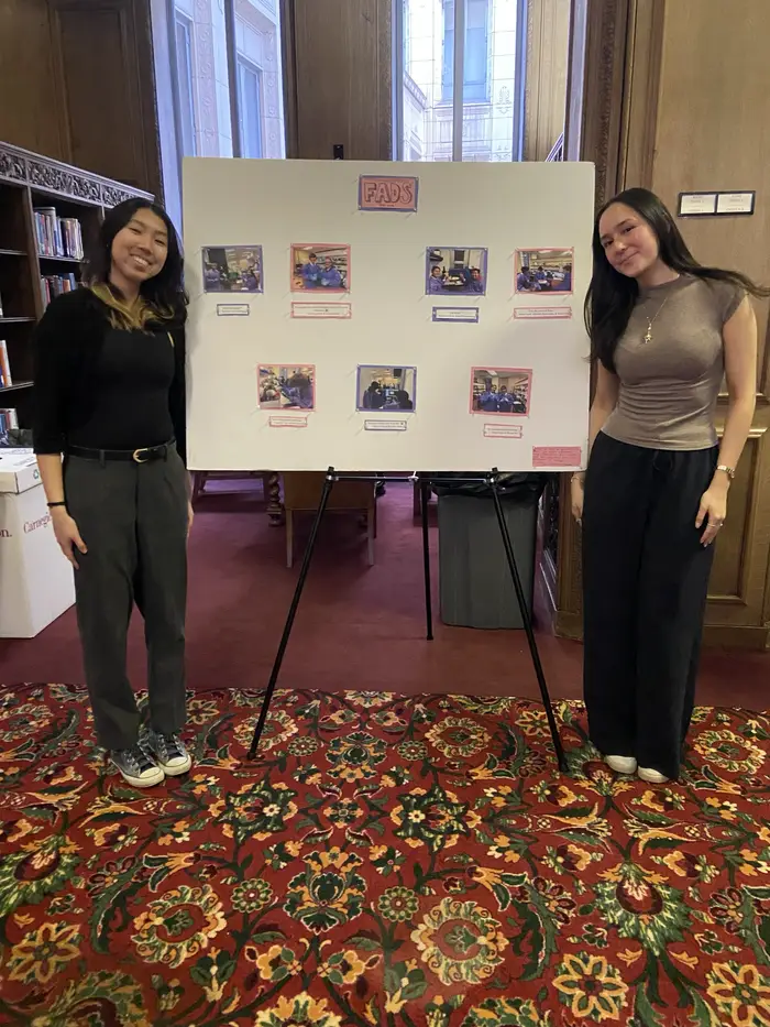Marissa and classmate pose in front of their research presentation.
