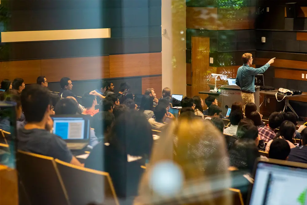 Looking through a window as a professor gives a lecture to a class.