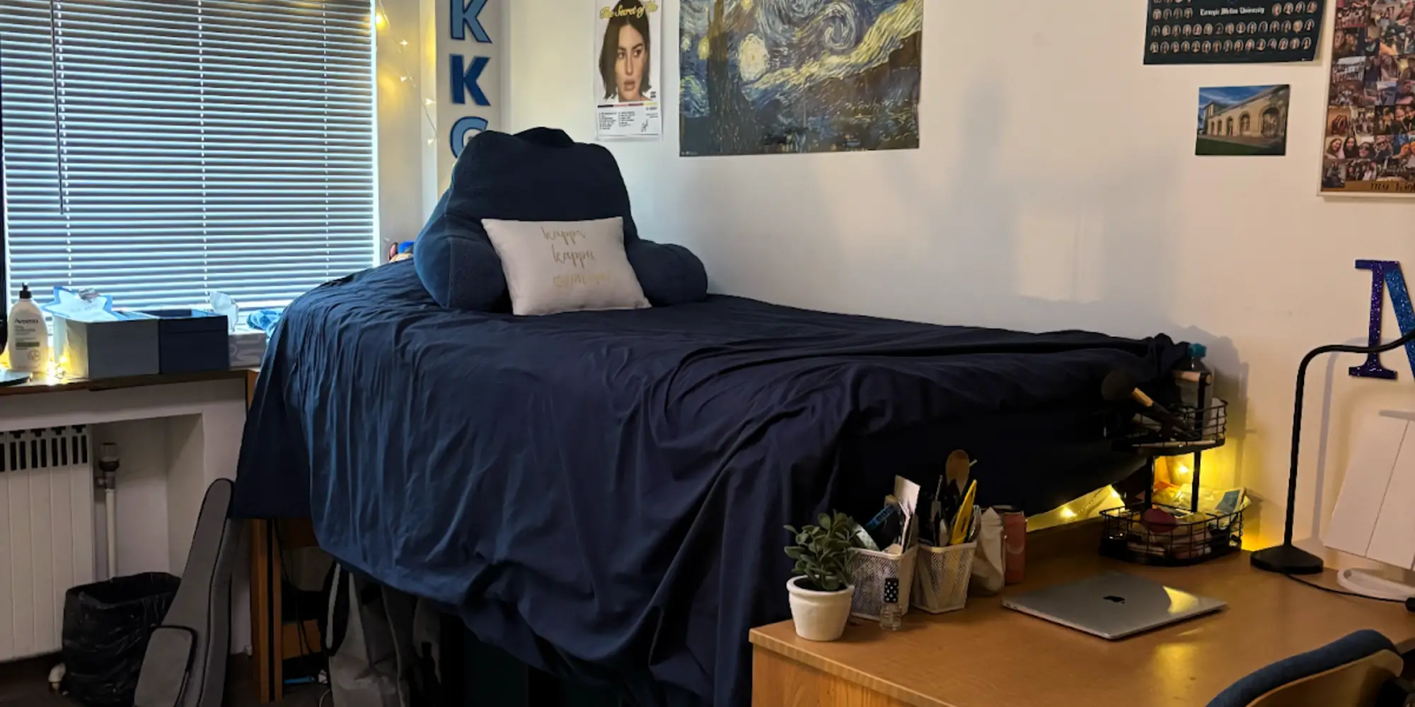 An image of Miriam's dorm room, showing her desk and bed with decorations on the wall.