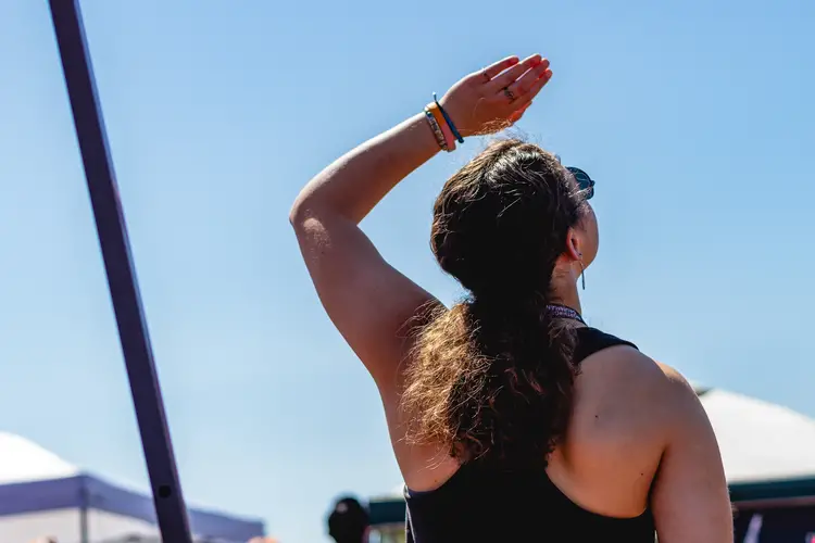 A member of CMRC shields her eyes from the sun as she watches a rocket launch.