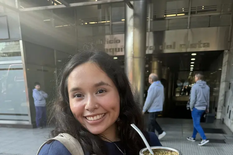 Student smiling at camera with cup in hand