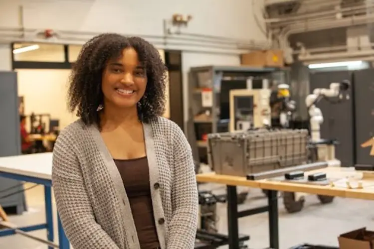 Photo of Beverly (Bev) Da Costa standing in a robotics lab.